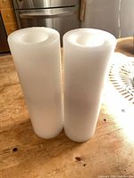Front view of both white pillar candles standing upright