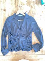 Front view of black silk blouse on hanger showing ruched detailing and collar