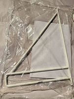 Single white metal triangular bracket in sealed bag