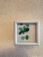 Top view of eight emeralds in display case