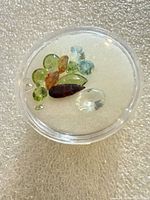 Assorted loose gemstones in plastic case on foam backing