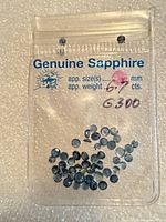 Front view of plastic pouch labeled Genuine Sapphire showing multiple blue stones inside