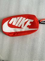 Front view showing white Nike logo on red-orange pencil case