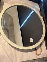 Front view of round mirror showing distressed frame and rope hanger