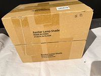 Two cardboard boxes labeled "Banker Lamp Shade" with dimensions and country of origin