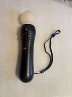 Full view of Sony PlayStation Move controller showing buttons, sphere and wrist strap