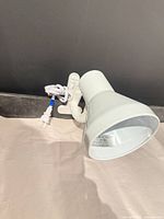 Front angled view of white clip-on gooseneck desk lamp showing shade and cord