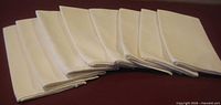 Eight folded white linen napkins arranged in a row