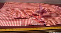 Folded red/white gingham tablecloth with napkins displayed