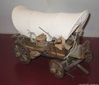 left side view showing wagon body, canvas top, barrel, wheels