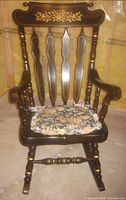 Front view of dark stained wooden rocking chair with floral cushion