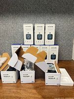 Stack of eleven ULTRALOQ Wi-Fi smart deadbolt lock boxes, some open showing contents