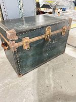 Front view of steamer trunk showing brass latch, metal bands, studded trim