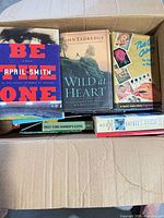 Open box showing several book covers including Be The One, Wild at Heart, Oil Coloring for Fun or Profit, First-Time Farmer's Guide, Sophie's World