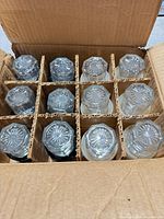 Box interior showing 12 clear glass shakers separated by cardboard dividers