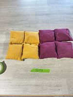 All eight beanbags laid out, four gold four maroon