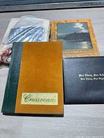 Lot overview showing gown in plastic, Crossroads yearbook, Rhododendron yearbook and diploma holder