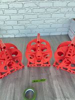 Three identical orange plastic cord reel winders on floor