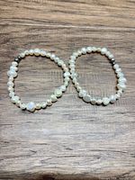 Both pearl bracelets side by side on wood surface