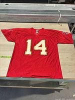 Full view of red Buccaneers jersey laid flat showing number 14 front