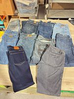 Eleven pairs of jeans laid out on table