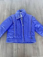 Front view of blue puffer jacket laid flat