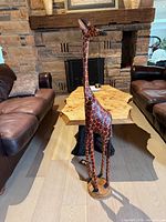 Front view of 48" hand-carved wood giraffe sculpture standing between sofas