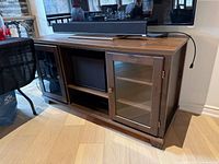 Front view showing overall TV stand with glass doors and open shelf