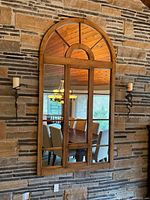 Full view of large arched mirror mounted on stone wall