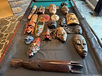 All 19 masks laid out on black cloth over pool table