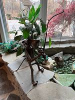 Full view of welded metal dog fishing sculpture on stone ledge