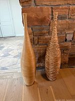 Both floor vases standing side by side against stone wall