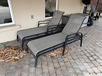Two of the four matching chaise lounge chairs showing frame, fabric, and reclining backs