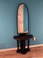 Console table with attached tall oval mirror against wall