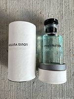 Louis Vuitton Imagination perfume bottle next to opened white cylindrical case