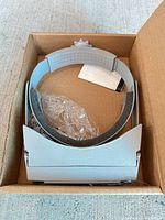 Headband magnifier in open box with plastic wrap and insert visible