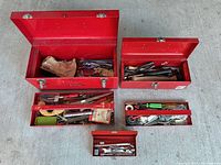 overview of five red toolboxes and contents spread on floor