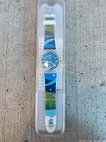Full view of Olympic Swatch watch inside clear plastic case