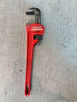 Full view of red 14" Forester pipe wrench on concrete