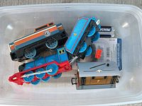 Plastic bin containing four Thomas & Friends TrackMaster locomotives and tender