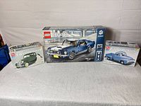 Overview showing three boxed Ford-themed kits: LEGO Mustang and two AMT model kits