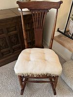 Full view of wooden rocking chair with ivory cushion