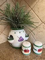 Front view of ceramic herb planter and matching salt and pepper shakers placed on countertop