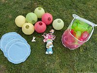 All items laid out on grass: paper lanterns, placemats, two bunny figurines, bag of neon cups