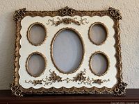 front view showing entire ornate cream and gold frame with five oval openings