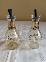 Front view of both Pyrex cruets showing Oil and Vinegar labels and stoppers
