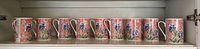 Full row of ten identical floral mugs on shelf