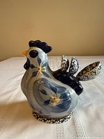 left side view of ceramic rooster holder with three spoons inserted