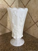 Full view of milk glass vase showing scalloped rim and embossed grape pattern