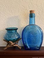 Blue Wheaton Horseshoe Bitters bottle, blue vase, wooden stand